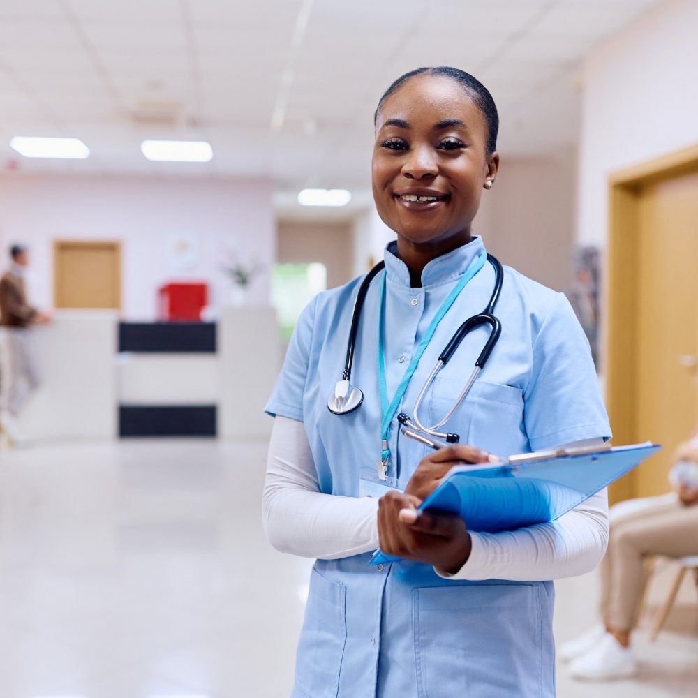 Portrait of happy black nurse at medical clinic looking at camera.