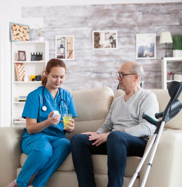 Pretty young nurse in nursing home giving medication